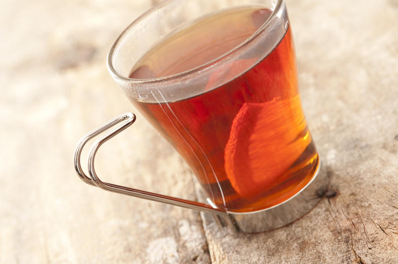 Transparent glass cup of freshly brewed lemon tea with a slice of fresh lemon view high angle tilted on a wooden table