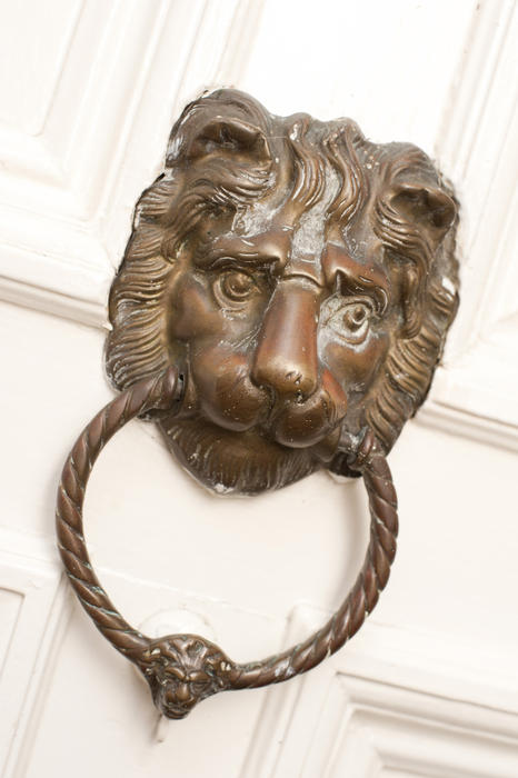 Close up Vintage Metal Lion Head Knocker on a White painted wooden front door