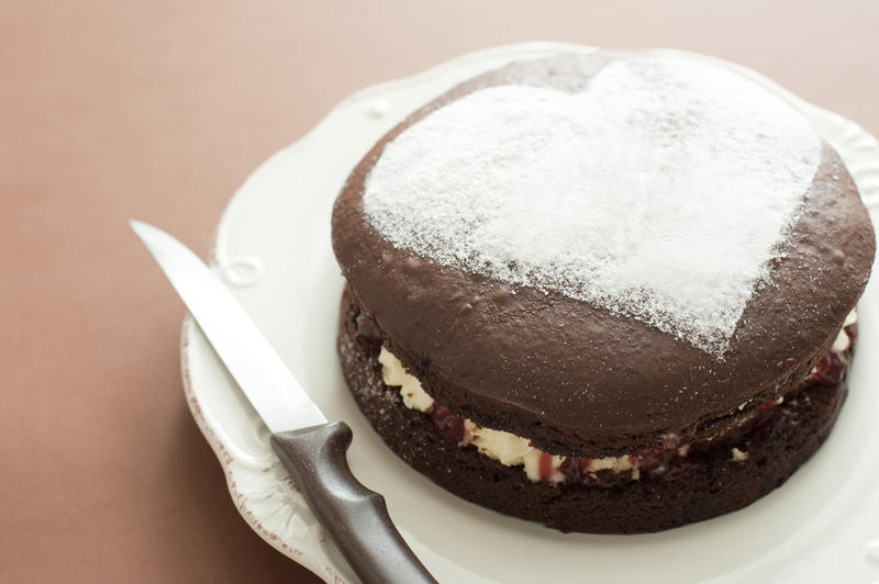 Freshly baked chocolate cake with a heart shape in icing sugar on the top symbolic of love and romance, anniversary or Valentines Day