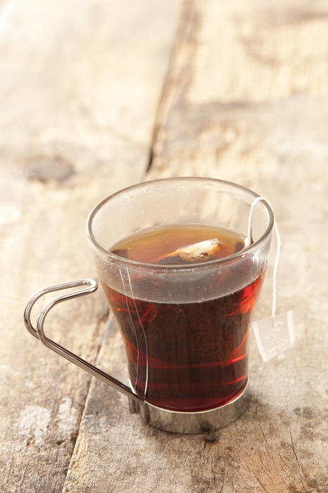 Close Up of Tea Bag Steeping in Glass Mug - Still Life of Fresh Brewed Black Tea in Glass on Rustic Wooden Table