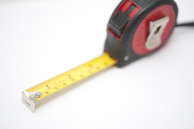 Imperial and metric builders tape measure marked in inches and centimetres on a white background with selective focus and copyspace