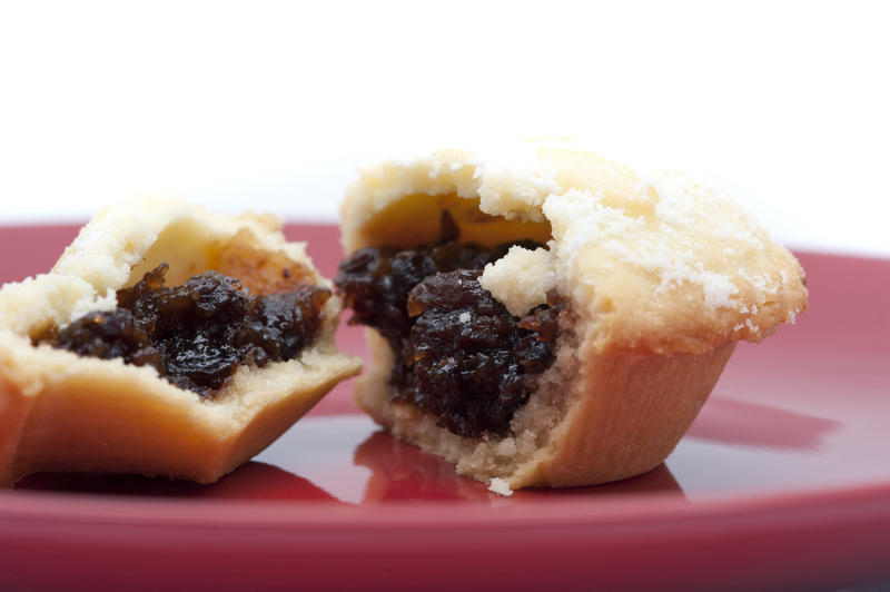Detail of a fresh fruity Christmas mince pie broken open on a plate to reveal the rich filling of dried fruit and spices