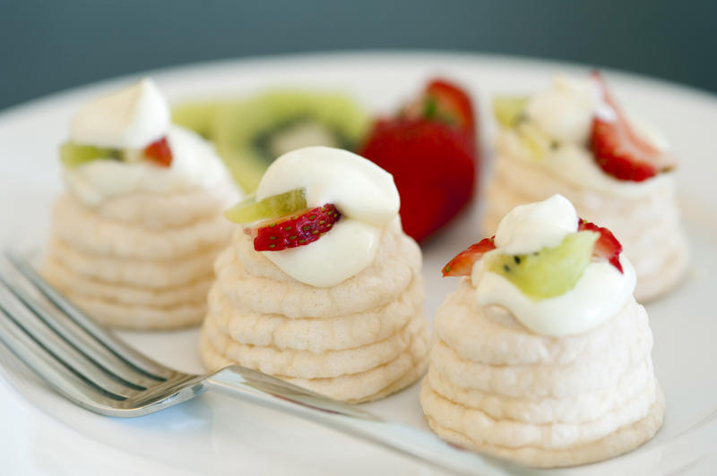 Indiviual meringue pavlovas with decorative twirled cases filled with whipped cream, strawberries and kiwi fruit