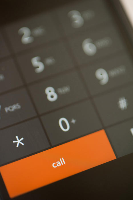 Close up Orange Call Dial Button below Numbers and Symbols on a Modern Touch Screen Mobile Phone