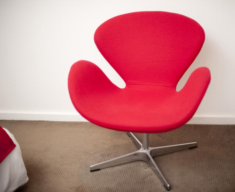 Modern retro-style furniture with a bright red modular chair on a steel base against a white wall