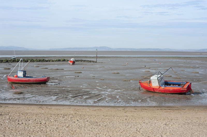 Fishing boats beached on the sand by the receding tide in the harbour at Morecambe, Lancashire