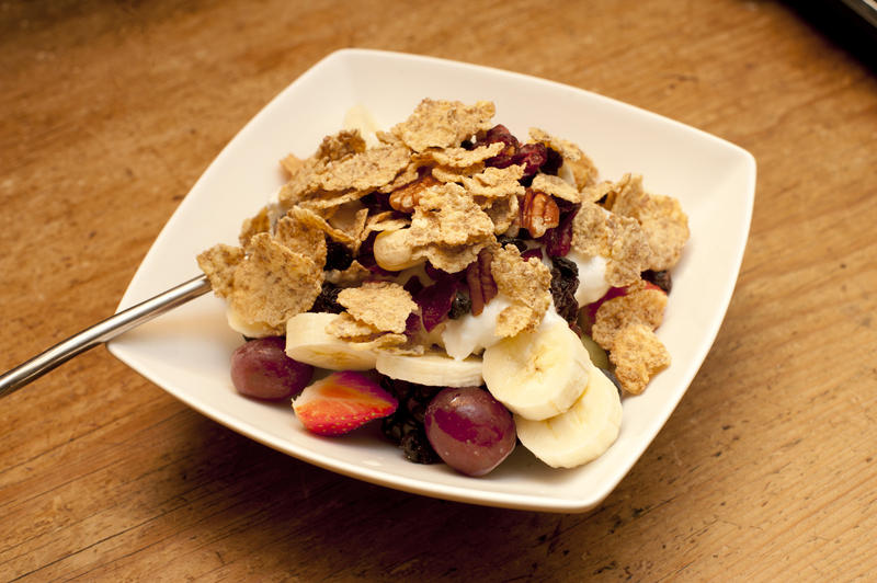 Healthy serving of breakfast cereal with fresh fruit and yoghurt served in a modern square dish on a wooden table