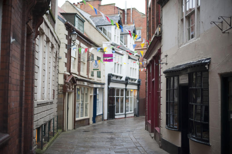 View of quaint storefronts lining the narrow cobbled street known as Grape Lane in Whitby
