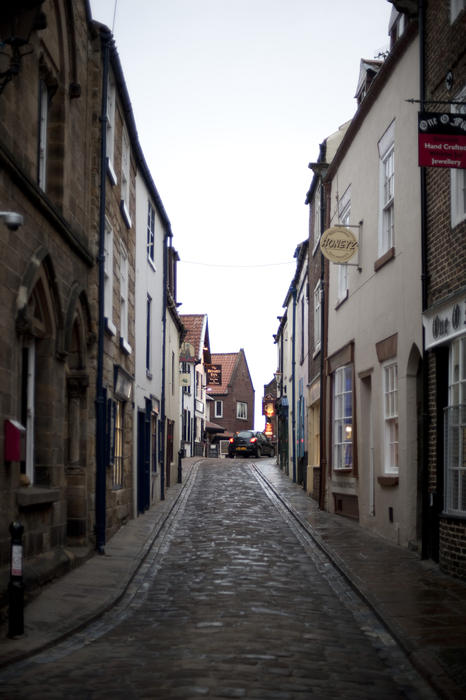 View up the historical narrow cobbled lane of Church Street in Whitby which leads from the town to the foot of the 199 steps leading up to St Mary's Church
