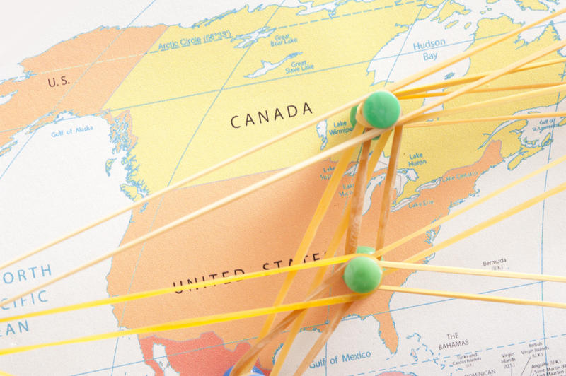 Close up North America Links Concept Using Map with Pins Connected with Elastic Rubber Bands.