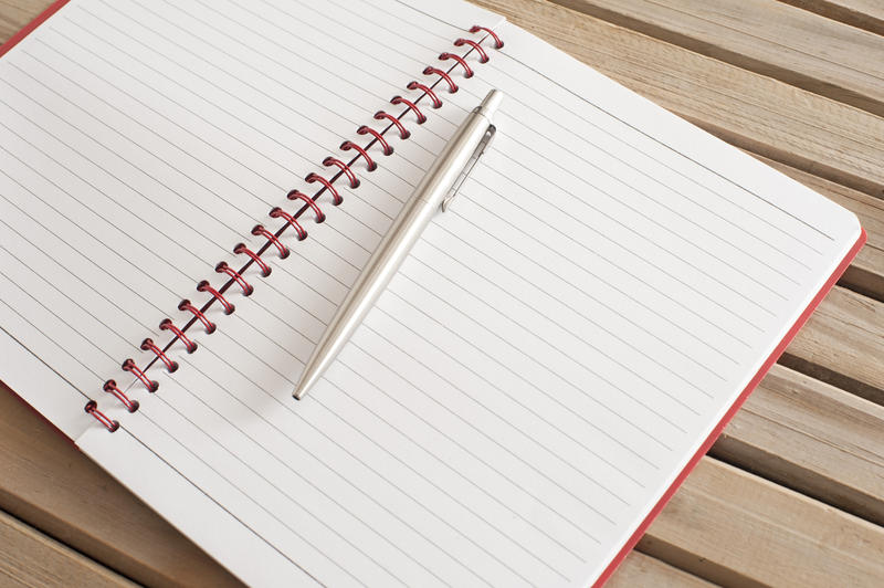 Close up Open Blank Spiral Notebook with Silver Ballpoint Pen on Top Placed on Top of Wooden Table, Emphasizing Copy Space.