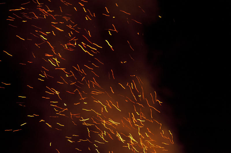Orange embers flying into the night sky carried by the draught created by a roaring bonfire, festive or celebration background image