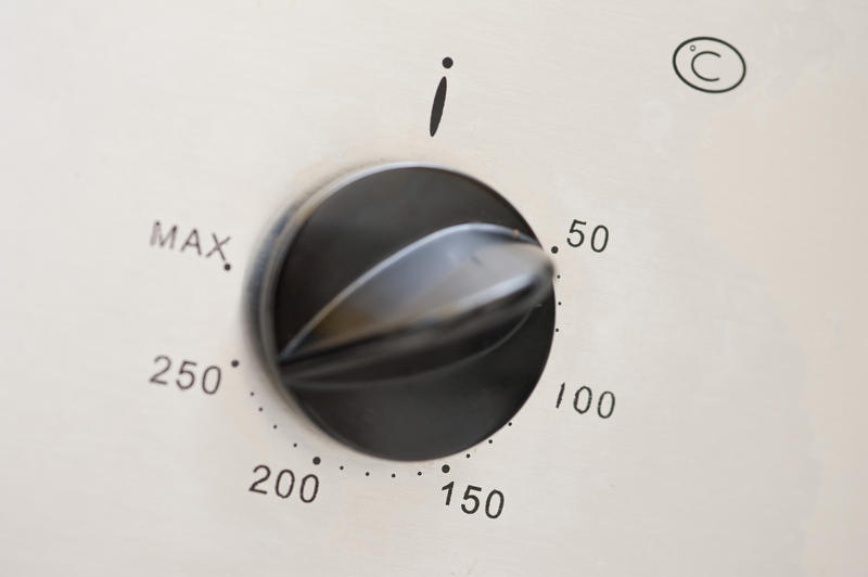Temperature control on an oven with a circular dial and knob showing a range of different thermostatic temperature settings