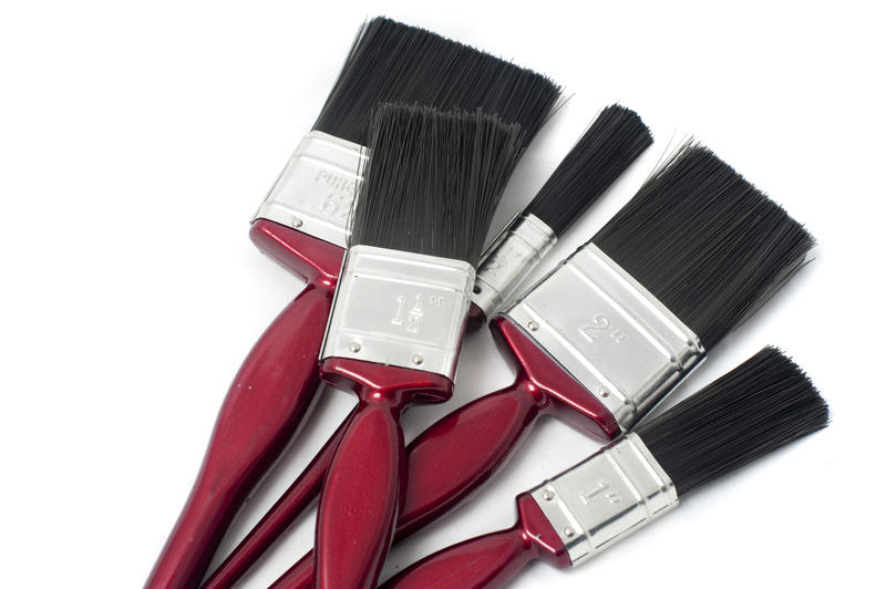 Set of new interior decorating paintbrushes for painting the walls and woodwork in a home in increasing sizes in a random pile on a white background