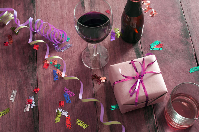 a pink tinted party still life with drinks glasses, streamers and a wrapped gift