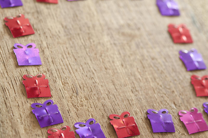 A border of birthday gift shapes on a wooden surface