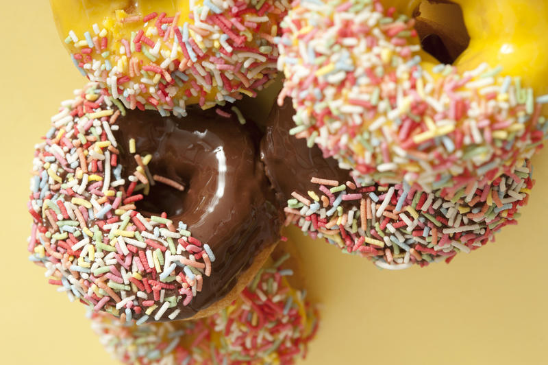 Glazed ring donuts with multicolored sprinkles and colorful lemon and orange or rich chocolate icing