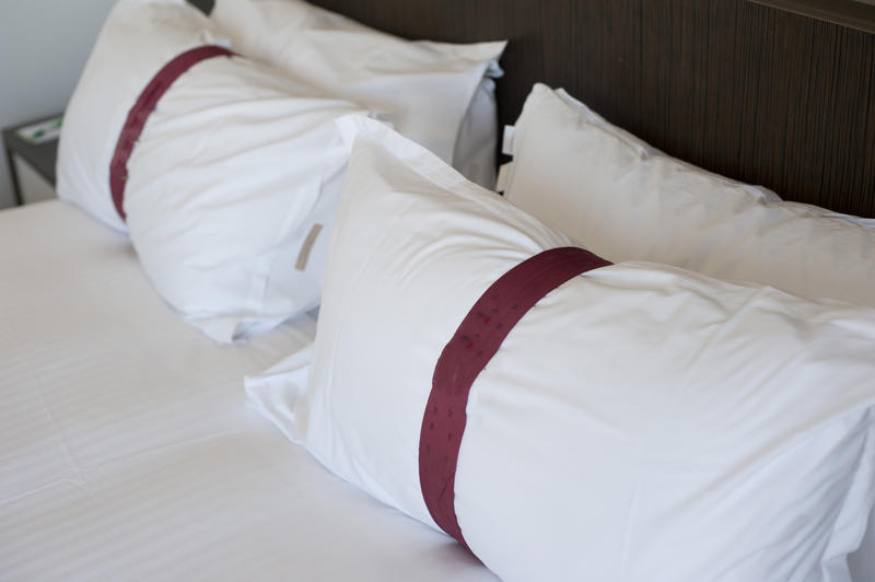 Fluffy comfortable white pillows with decorative purple bands on a hotel bed , close up view