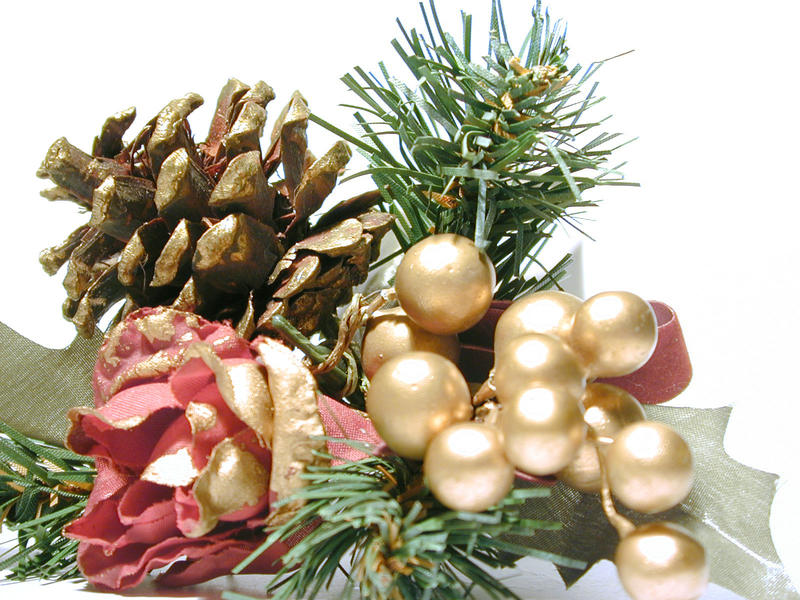 Pine cone Christmas decoration with a red rose, gold berries and green foliage to decorate the Xmas tree or table for dinner