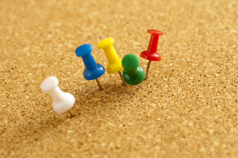 Close up Five Colored Sharp Pins Pinned on Brown Textured Cork Board