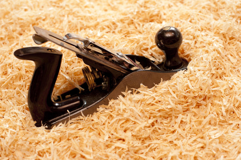 Handheld woodworking plane with an adjustable blade on a background of fresh wood shavings with copyspace