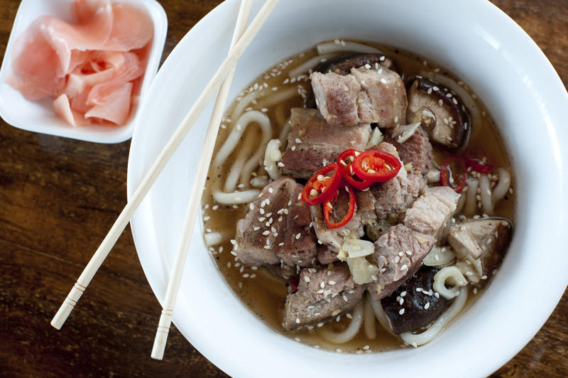 Bowl of ramen, a traditional Japenese meal of noodles in a broth, garnished with pork chunks, overhead view in a bowl