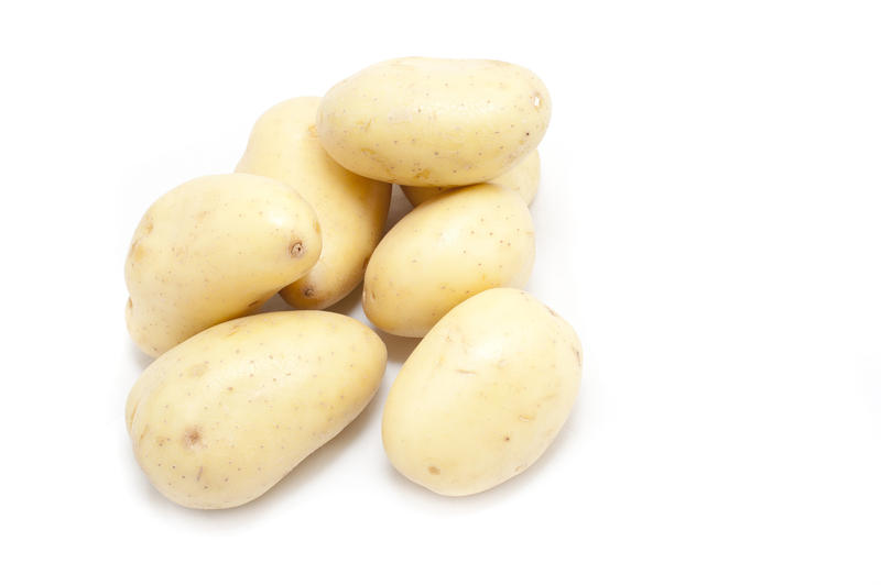 Farm fresh whole uncooked washed potatoes piled on a white background for a nutritious vegetable ingredient in cooking and vegetarian cuisine