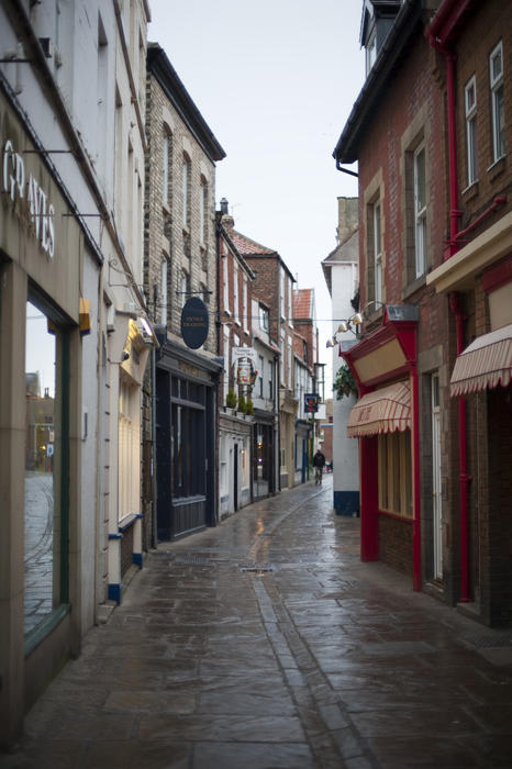 A narrow cobbled sett stone alley way in whitby with quaint shops