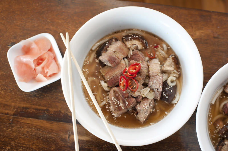 Japanese ramen, a tradional meal of noodles in a broth garnished with cooked pork and vegetables, overhead view