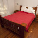 8938   Classic wooden bed with a red bedspread