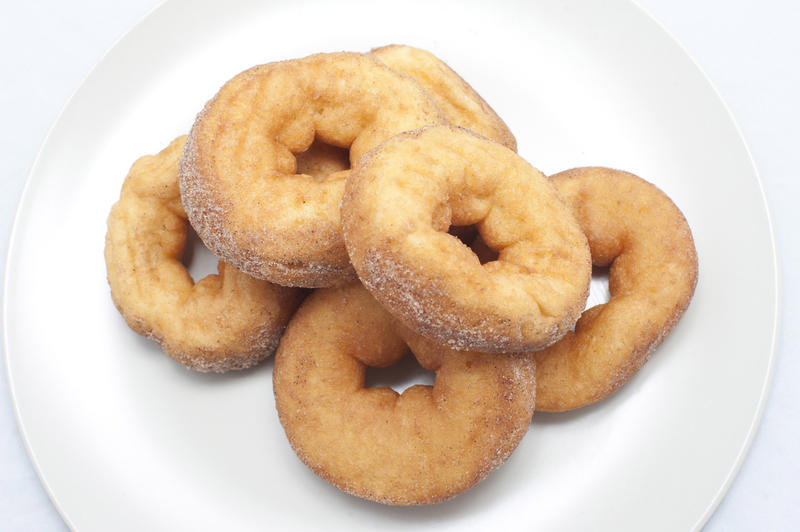 High angle close-up of ring doughnuts powdered with vanilla sugar in a white plate