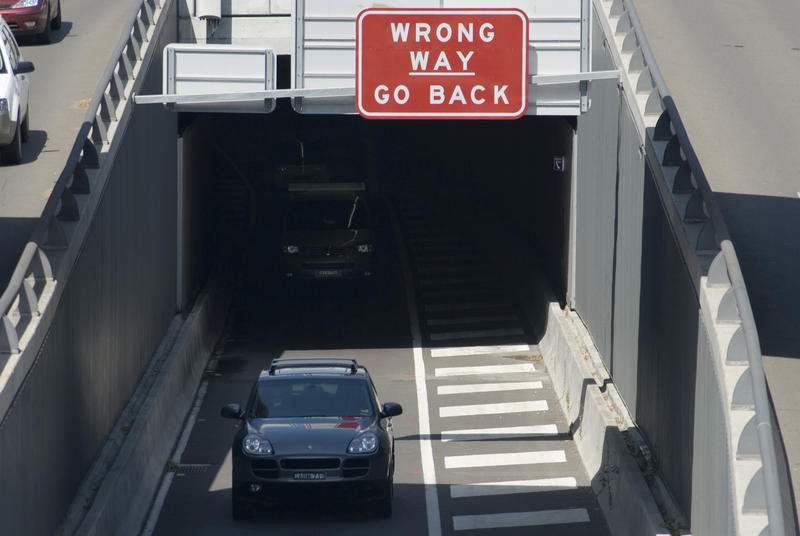 Overview of Cars Exiting Tunnel in Urban Street Environment with Warning Sign Indicating Wrong Way