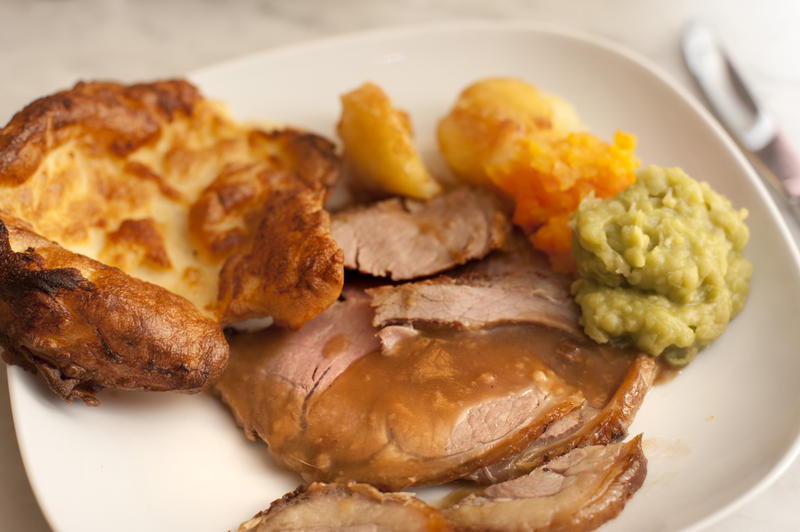 Delicious sliced roast beef and Yorkshire pudding served with gravy and vegetables for a tasty dinner, close up of the plate of food