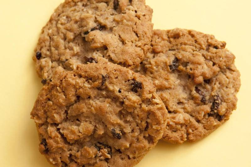 Trio of rustic crunchy oat cookies or biscuits for a tasty snack at teatime or between meals, close up on yellow