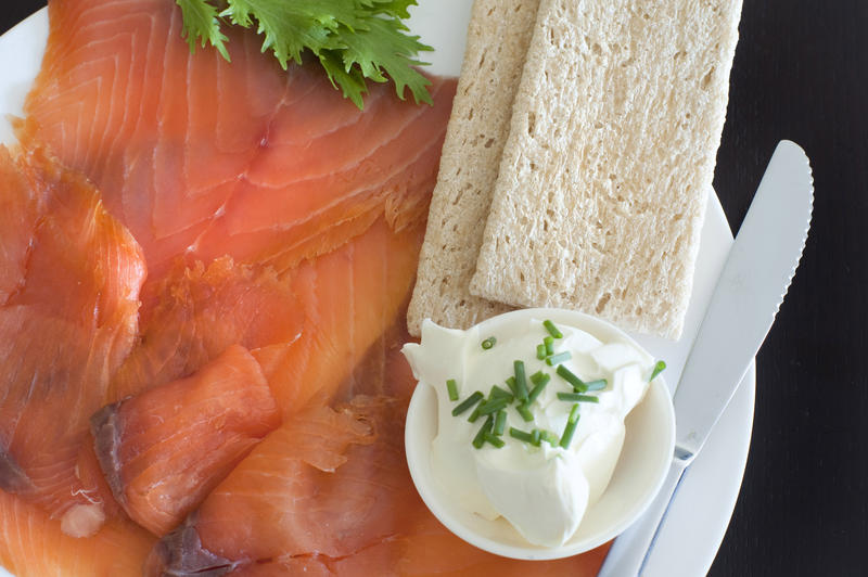 Gravlax or thinly sliced smoked salmon served as a gourmet meal with a side dish of cream cheese and chives and wheat crsipbread