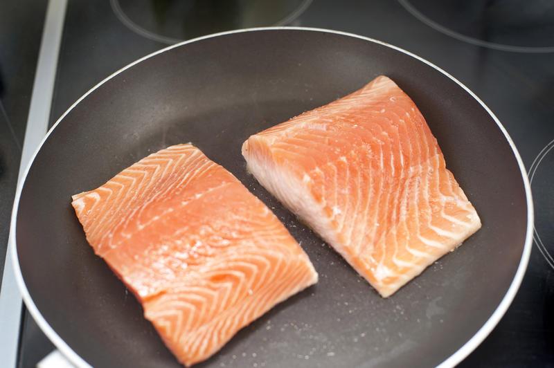 Pan frying fresh salmon steaks for a healthy seafood meal rich in omega-3 fatty acids