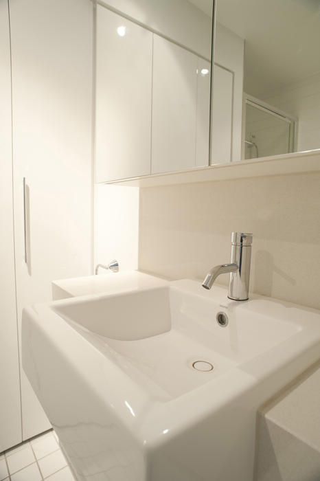 Plain white rectangular ceramic hand basin in a monochrome white bathroom with mirror and cabinets