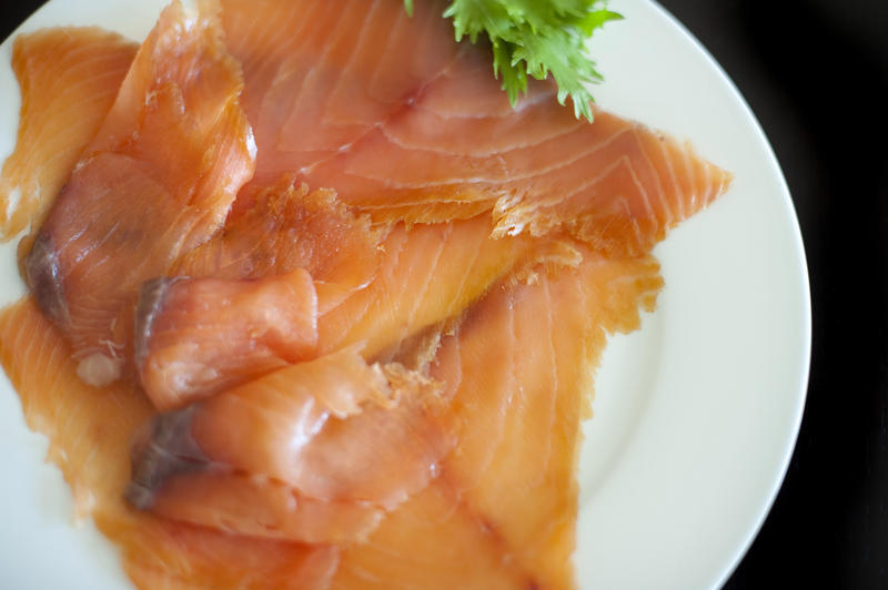 Overhead view of a plate filled with gourmet smoked salmon slices garnished with parsley