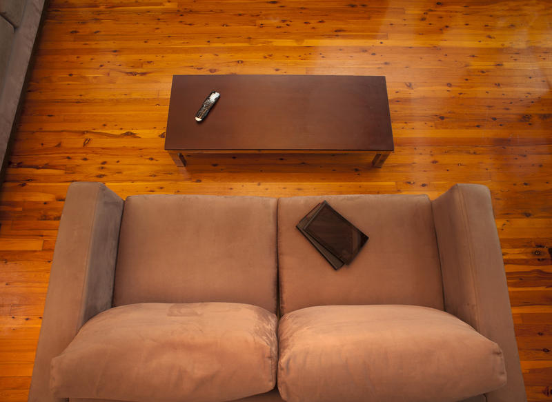 View from above of an empty comfortable brown upholstered lounge sofa and coffee table on a wooden floor