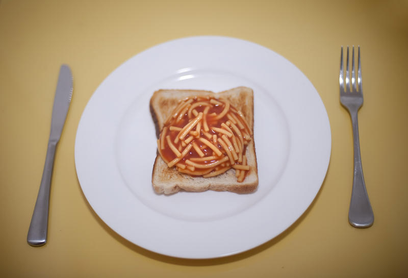 Slice of white toast and tinned spaghetti in tomato sauce served on a plate for a quick convenient cheap snack