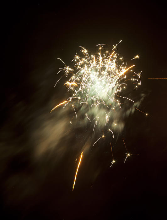 Sparkling exploding fireworks with a colorful golden rocket bursting in a shower of sparks in the night sky during a festive celebration