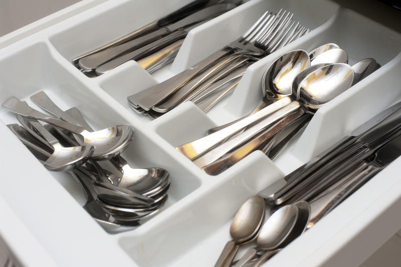 Open cutlery drawer in a kitchen unit with separate divisions for spoons, forks and knives