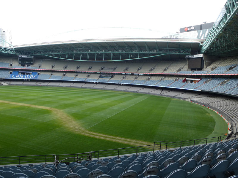 Empty sports stadium with tiered seating around a green sports field for field events such as football or soccer