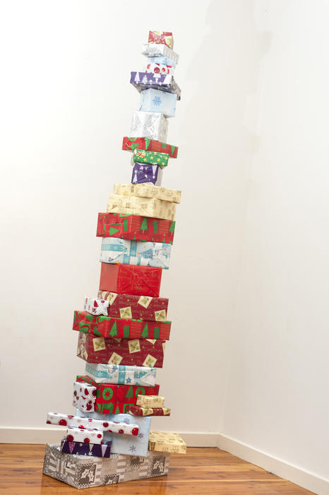 Tall stacked tower of Christmas gifts making a unique colourful decoration in the corner of a room