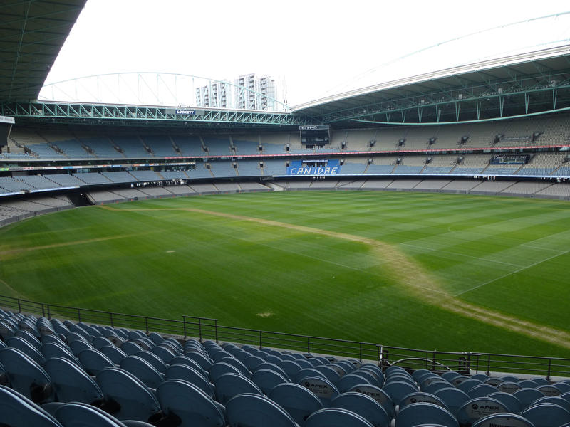 Empty sports stadium with tiered seating and a grassy sports field stadium with a pitch