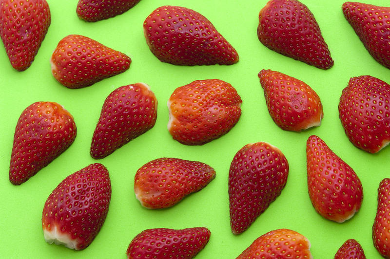 Colourful background of halved ripe red strawberries on green making a striking pattern concept for strawberry dessert