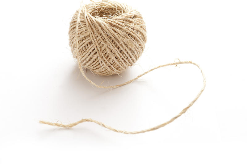 Ball of household string or twine from twisted natural hemp fibers on white