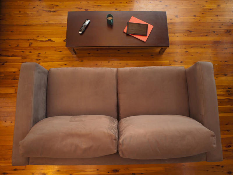Overhead view of a comfortable living room with a brown upholstered couch and wooden coffee table on a hardwood floor