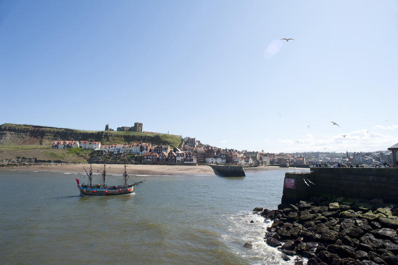 View of St Marys Church on Tate Hill in Whitby with the Bark Endeavour replica of Captain Cooks ship sailing up towards the River Esk