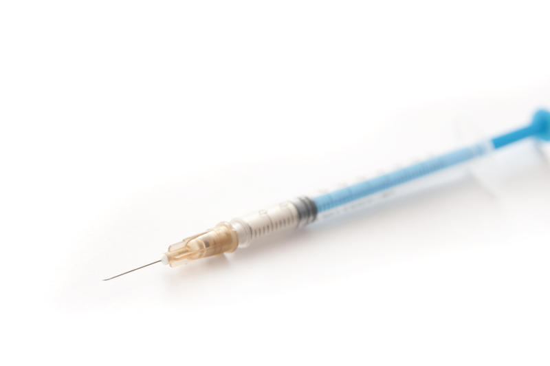 Small disposable plastic syringe or hypodermic with needle for administering medication subcutaneously in diseases such as diabetes, diagonally over white
